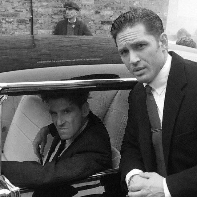 a man in a suit and tie sitting next to a man in a car
